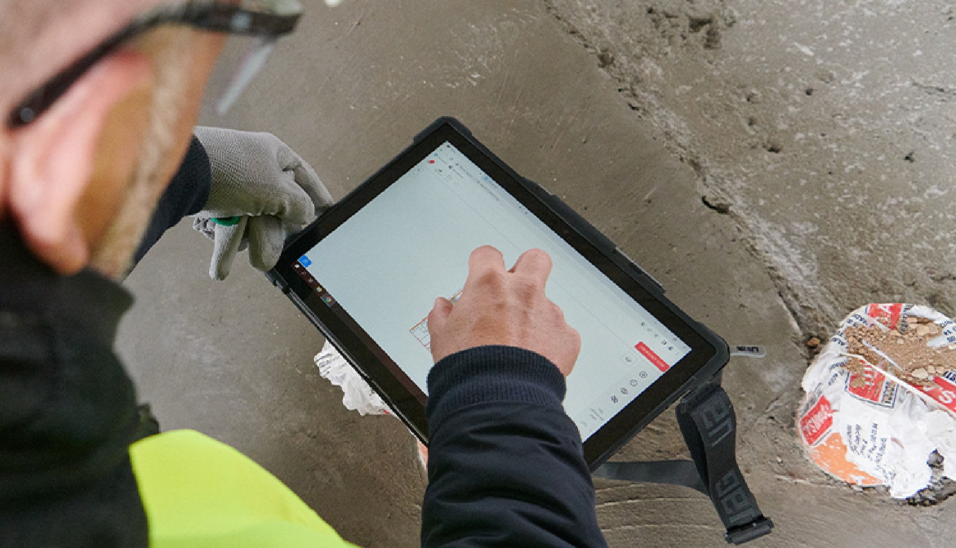 A construction worker using a tablet on a construction site.