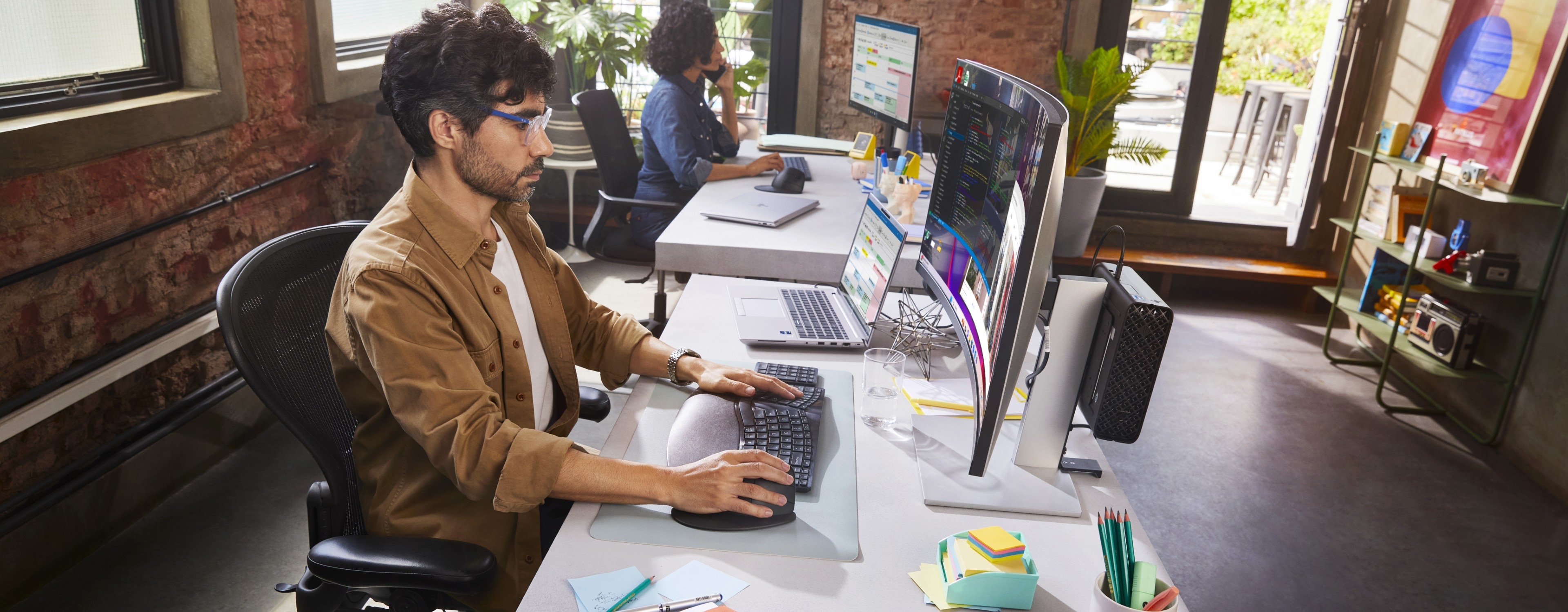 A man and woman working side by side in an office setting on their HP Business Computers