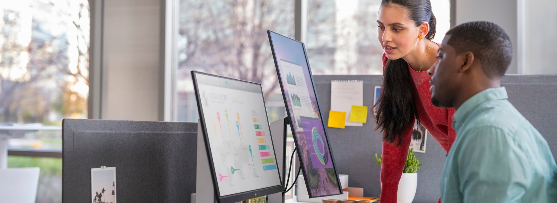Two coworkers using HP monitors, laptop and wireless keyboard.