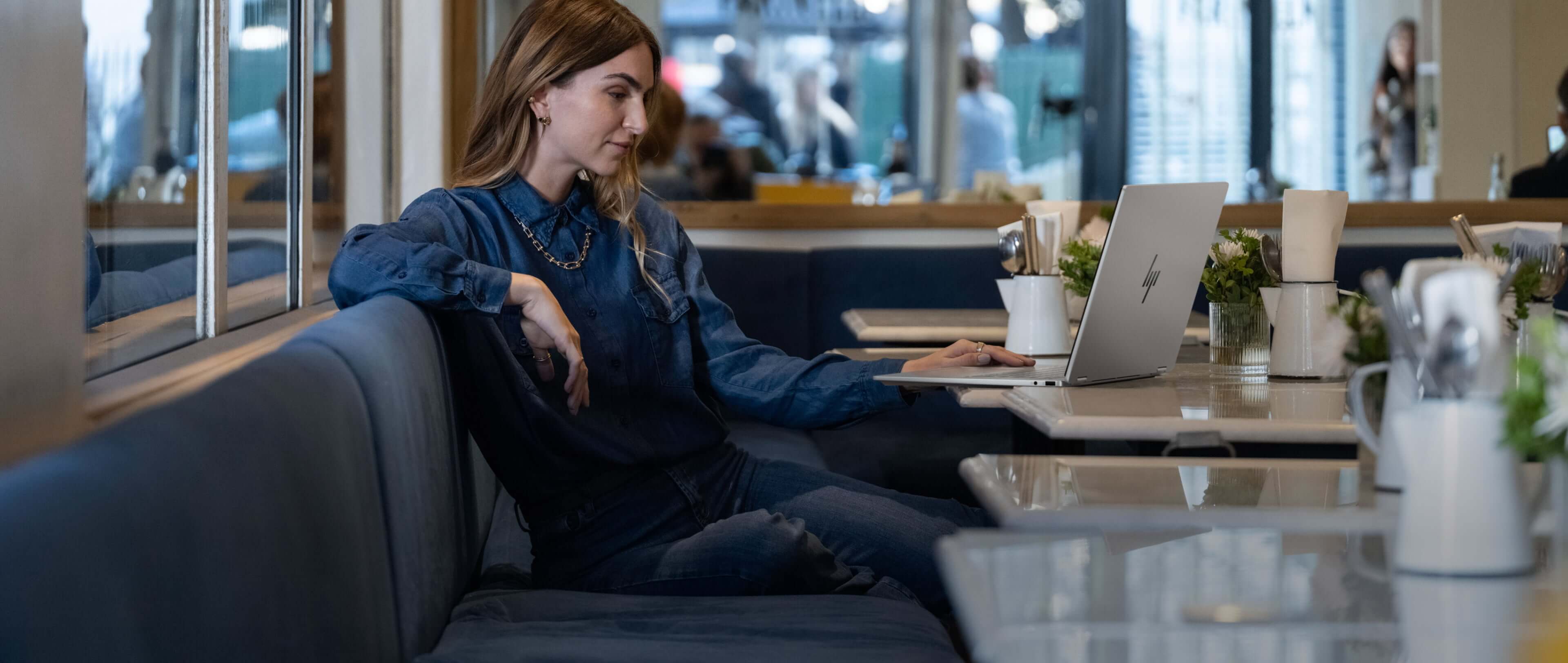 A person sitting in a cafe table with a HP OmniBook X laptop