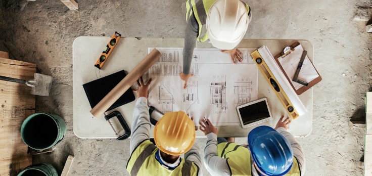 Electrical engineering team deciding on the placement of energy storage solutions for construction projects while finalizing blueprints
