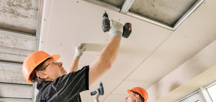 Drywallers installing drywall on the ceiling